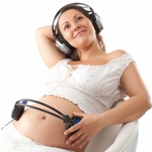 Беременная женщина слушает музыку вместе с ребенком